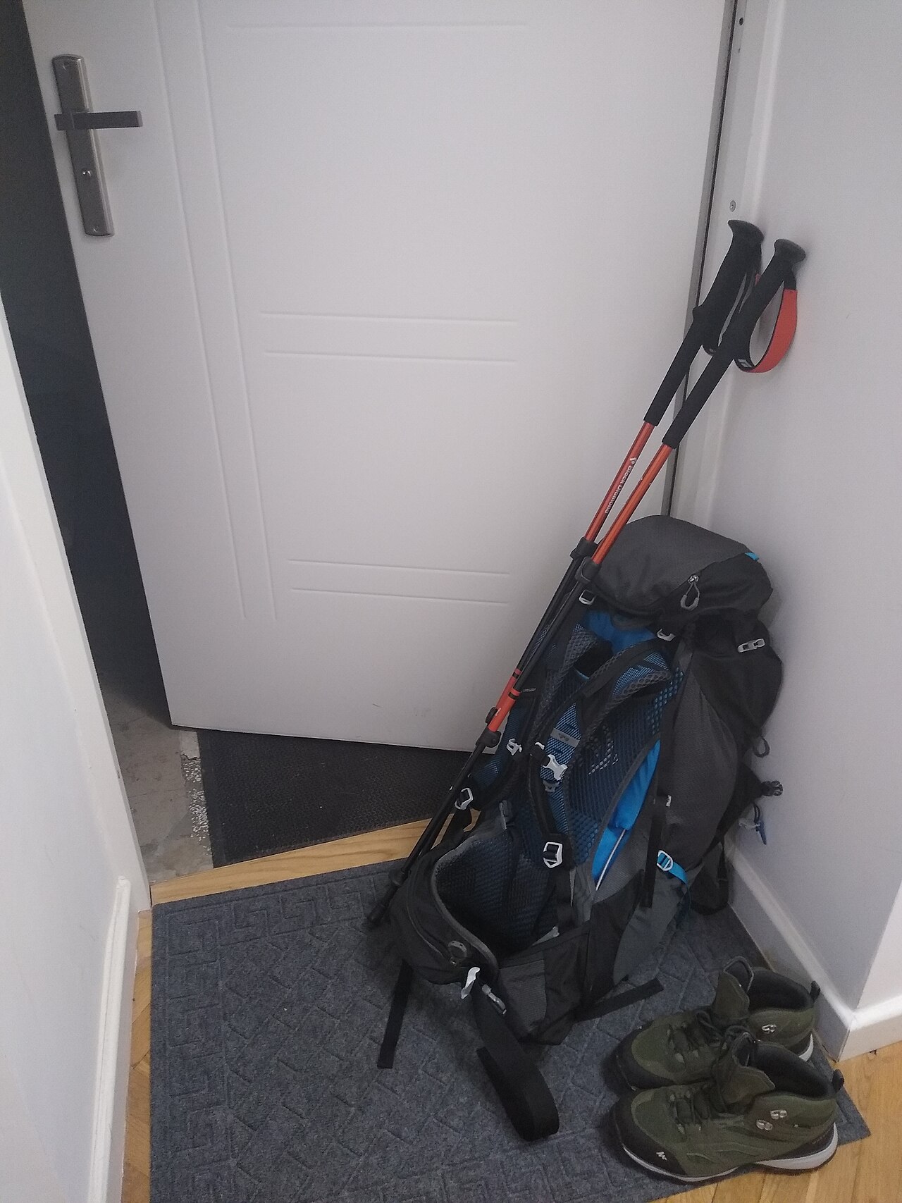 Mochila de senderismo apoyada junto a bastones y calzado de montaña